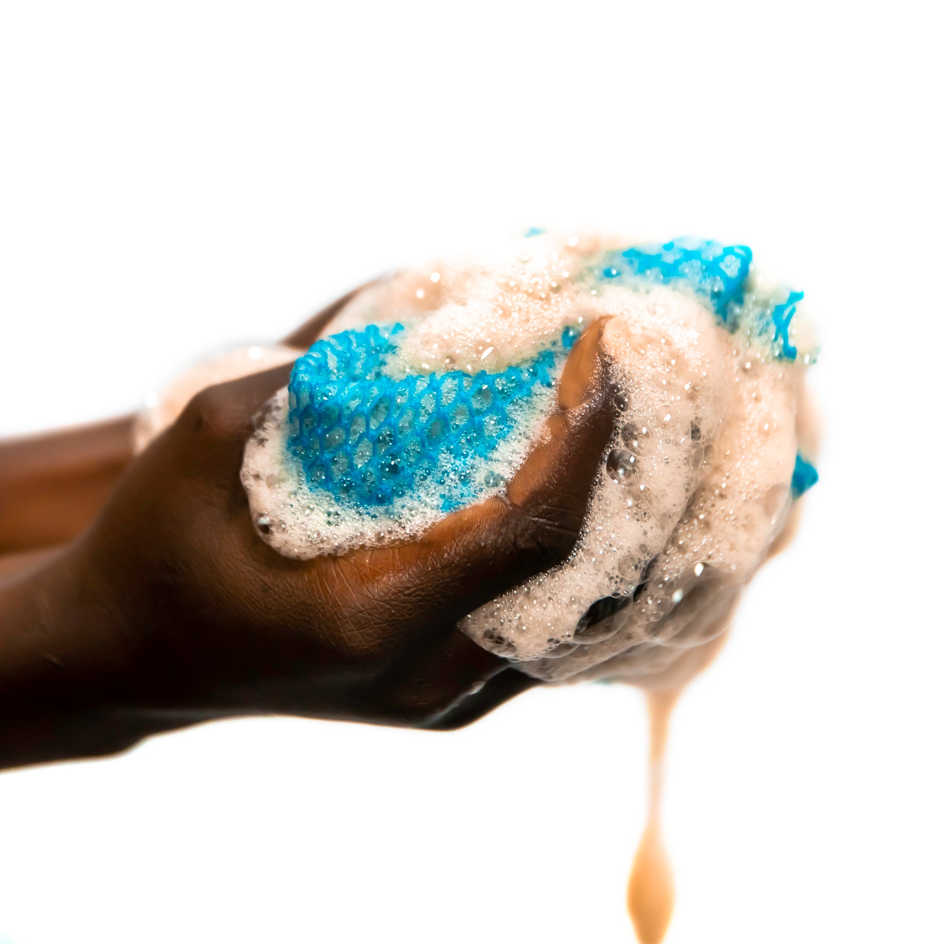 B Fly Liquid Black Soap Body Wash  squeezed on a B Fly Sapo Sponge, amber-colored liquid, enriched with Shea Butter, Neem Oil, and Palm Kernel Oil.